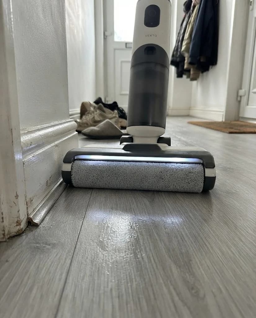 The Vekto Floor Washer F40 head on laminate with its LED strip lit, crumbs showing along the skirting board