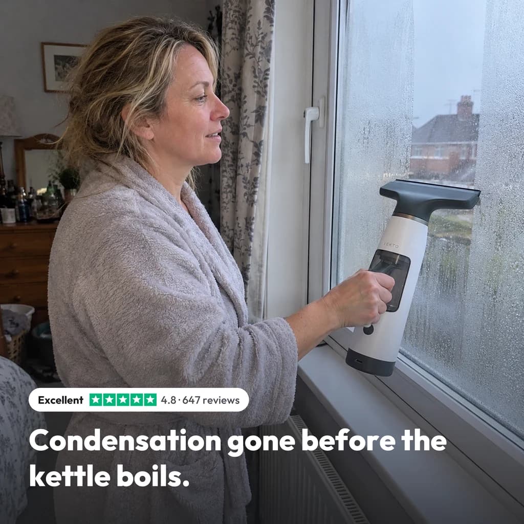 Condensation gone before the kettle boils: a woman drawing the Vekto Window Vac W10 down a fogged bedroom window, rated 4.8 from 647 reviews